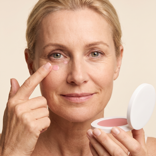 Vrouw brengt BrightLift oogcrème aan onder het oog, doosje in de hand